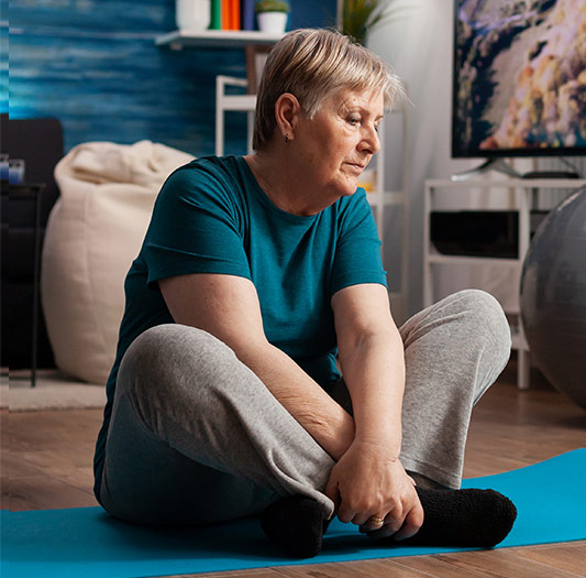 Woman sitting on yoga mat in her living room